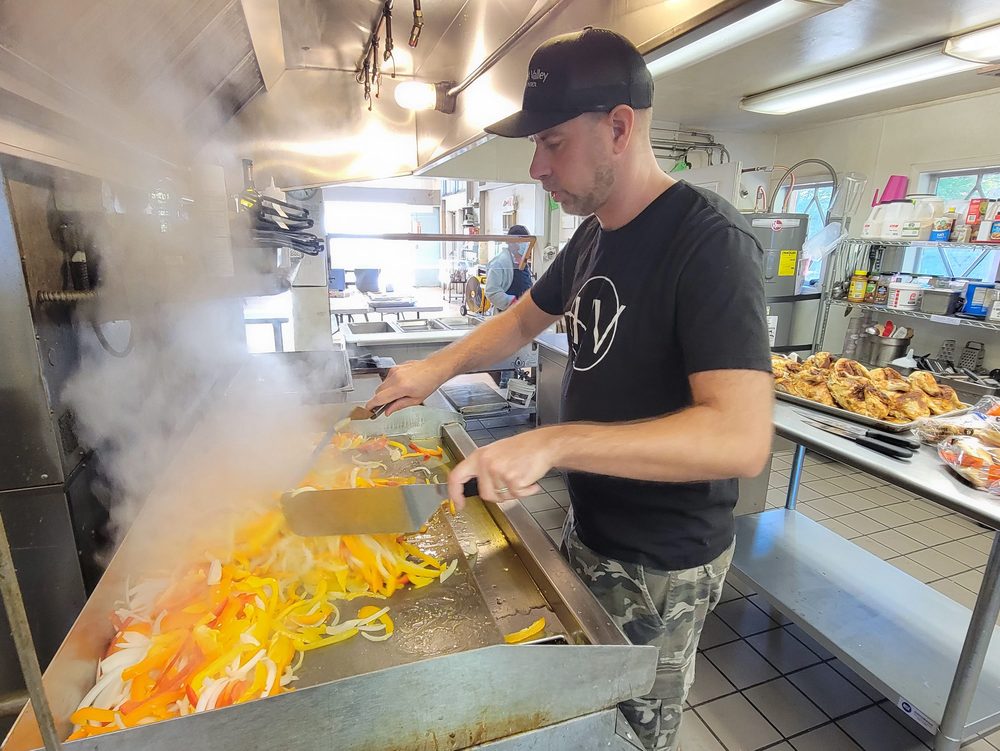 A volunteer cooking peppers and onions on the Mission’s kitchen griddle